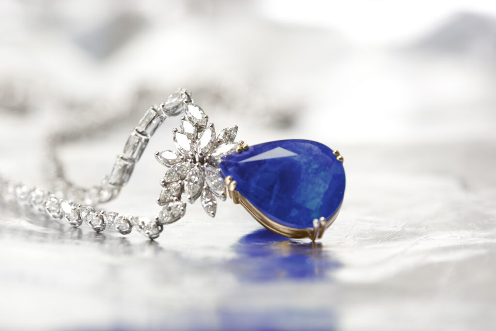 Pendentif en or serti d'une pierre bleue taille poire et de diamants, retouche photo bijouterie sur fond blanc.
